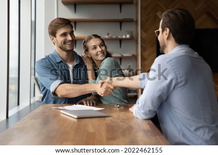 Happy excited couple of clients and lawyer giving handshakes. Married customers and real estate broker, agent, consultant, house seller shaking hands in office, celebrating property buying