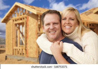 Happy Excited Couple In Front Of Their New Home Construction Framing Site.