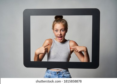 Happy Excited Cute Teen Girl Giving Some Attitude Posing Pointing At Herself, Looking Through Digital Tablet Frame Shouting