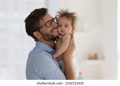 Happy Excited Dad Holding Sweet Baby Daughter In Diaper, Hugging Infant Kid With Cheek Touches, Cuddling With Love, Care, Affection, Laughing, Smiling. Fatherhood, Parenthood Concept