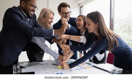 Happy excited diverse business team of different ages employees celebrating success, teamwork achieve, making hand stack of fists, keeping high motivation, friendship, community spirit - Powered by Shutterstock