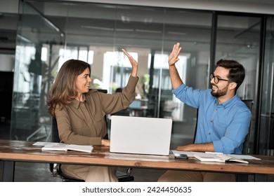 Happy excited executive business team two partners employees giving high five supporting celebrating professional success growth or financial work achievement sitting at office meeting with laptop. - Powered by Shutterstock