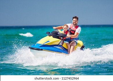 happy, excited family, father and son having fun on jet ski at summer vacation