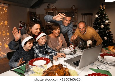 Happy and Excited family greeting their family and friends on Christmas eve using a skype video call during the coronavirus pandemic. Some relatives waving and talking to a laptop. Social distancing. - Powered by Shutterstock