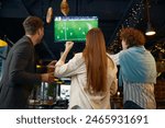 Happy excited group of friends watching football match on tv in pub
