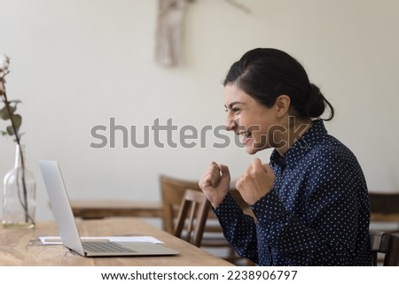 Happy excited Indian freelance business woman making yes fists, winner hand gesture at laptop, laughing, feeling joy, winning prize, money, getting good awesome news