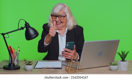 Happy Excited Joyful Senior Businesswoman Use Smartphone Typing Browsing Say Wow Yes, Great Big Win Good News Shocked By Sudden Victory At Office. Elderly Woman Isolated On Green Chroma Key Studio