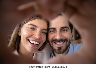 Happy excited married couple portrait with hand heart shaped frame. Young man and woman in love having fun, posing together, looking at camera, laughing, smiling. Relationship, Valentines day concept