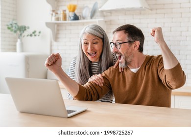 Happy excited mature middle-aged couple celebrating success in business, paying bills, lottery win, investment, startup, pension, refunds, payment at home using laptop