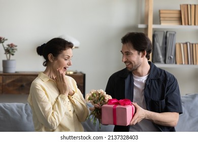 Happy excited mature mother getting present and flowers from grateful grown son, celebrating international women day, birthday, mothers day, receiving gift wrap, bouquet - Powered by Shutterstock