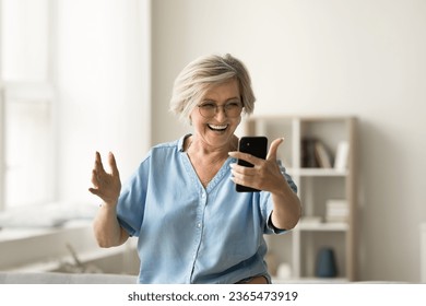 Happy excited mature older woman talking on video call on smartphone, enjoying funny conversation, laughing, taking selfie, having fun at home, using gadget for online communication - Powered by Shutterstock
