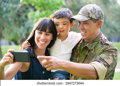 Happy Excited Military Man, His Wife And Little Son Taking Selfie On Cell Phone In City Park. Front View. Family Reunion Or Returning Home Concept