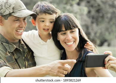 Happy Excited Military Man, His Wife And Little Son Taking Selfie On Cell Phone In City Park. Front View. Family Reunion Or Returning Home Concept