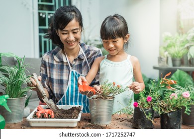 Happy Excited Mother And Her Daughter Gardening Together Plants Some Flower At Home