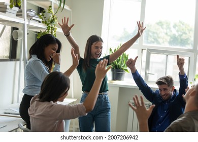 Happy excited multiethnic team proud of good job result, meeting in office, celebrating business success, win, achieve, making winner gestures, laughing, shouting, having fun, enjoying party