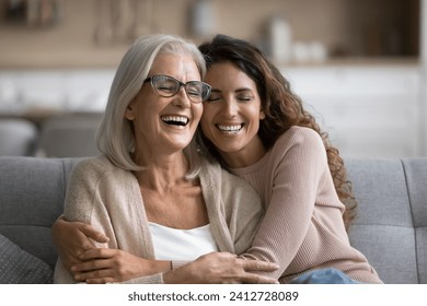 Happy excited senior mom and adult daughter woman having fun at home, hugging with heads touch, sitting on sofa, laughing with closed eyes, enjoying funny talk, leisure, family affection - Powered by Shutterstock