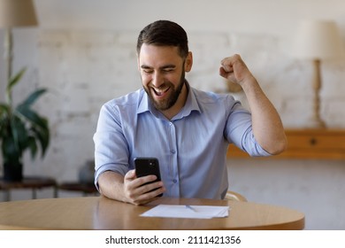 Happy excited smartphone user enjoying win, success, achieve, high job result. Euphoric businessman using cellphone, reading text message, feeling joy, making hand winner gesture, laughing