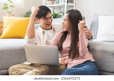 Happy excited, smiling asian young couple love using laptop computer, great deal or business success, received or getting cash back, tax refund, good news by mail while sitting in living room at home. - Powered by Shutterstock