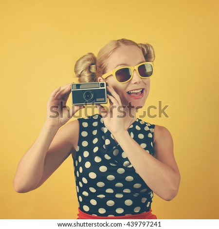 A happy excited vintage woman is holding a photography camera with glasses. Use it for an art, retro style or beauty concept.