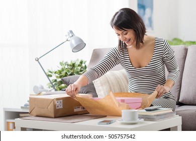 Happy Excited Woman At Home, She Has Received A Postal Parcel And She Is Unboxing Her Gift, Delivery And Online Shopping Concept