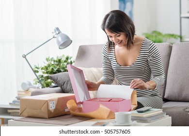 Happy Excited Woman At Home, She Has Received A Postal Parcel And She Is Unboxing Her Gift, Delivery And Online Shopping Concept