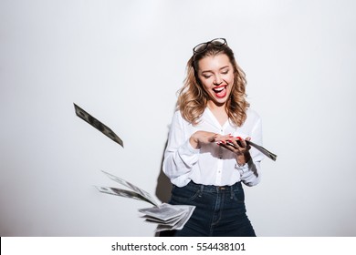 Happy excited woman throwing money over white background