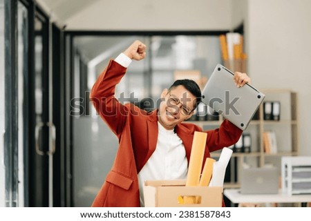 Happy and excited young  Asian man office worker celebrating her resignation, carrying her personal stuff. leaving job, changing or company.in modern office