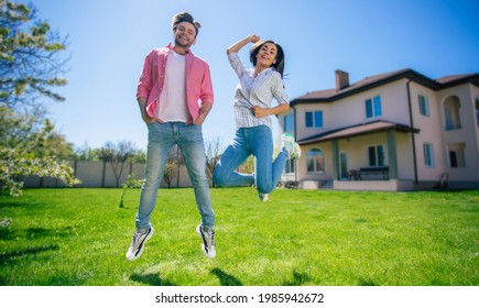 Happy Excited Young Couple Or Wife And Husband In Love Jumping In Front Of The New Big House While They Celebrating This Buying