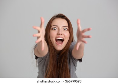 Happy Excited Young Woman Shouting And Reaching Hands To Camera Over Grey Background