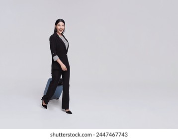 Happy executive asian businesswoman walking in an empty airport hall with a suitcase in work related business trip isolated on studio white background. - Powered by Shutterstock