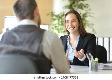 Happy Executive Coworkers Laughing And Talking Sitting On A Desk At The Office