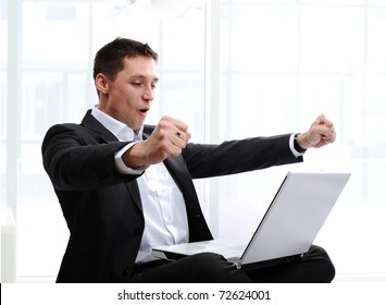 Happy executive raising fists in excitement, in front of laptop