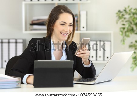Happy executive working with multiple devices at office