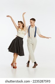 Happy, expressive professional dancers in 60s american fashion style clothes dancing rock-and-roll dance isolated on white background. Music, energy, happiness, mood, action