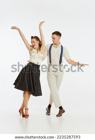 Happy, expressive professional dancers in 60s american fashion style clothes dancing rock-and-roll dance isolated on white background. Music, energy, happiness, mood, action