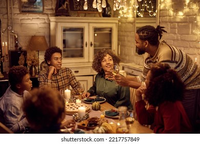 Happy Extended African American Family Talking While Gathering For Dinner On Thanksgiving At Dining Table. 