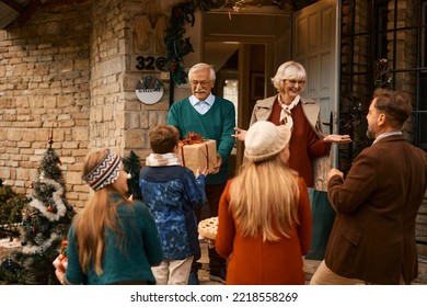 Happy Extended Family Gathering At Home For Thanksgiving. Focus Is On Mature Couple At The Doorstep.