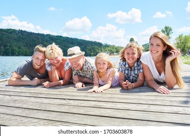 Happy Extended Family With Grandparents And Children Relaxed At The Lake In Summer Vacation