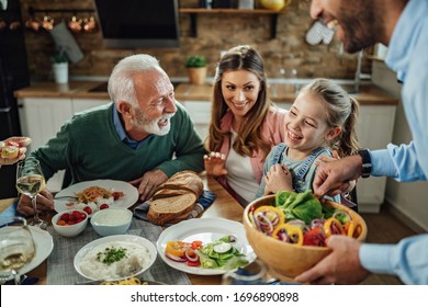 Happy extended family having fun while talking during lunch in dining room. Focus is on little girl.  - Shutterstock ID 1696890898
