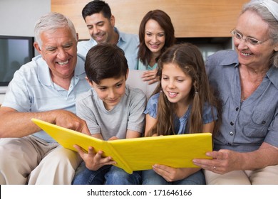 Happy Extended Family Looking At Their Album Photo In The Living Room