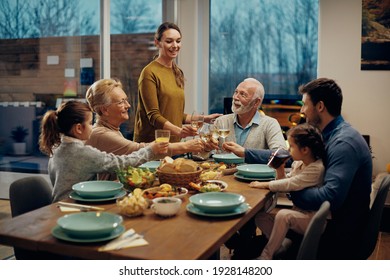 Happy Extended Family Toasting While Having Lunch Together In Dining Room.