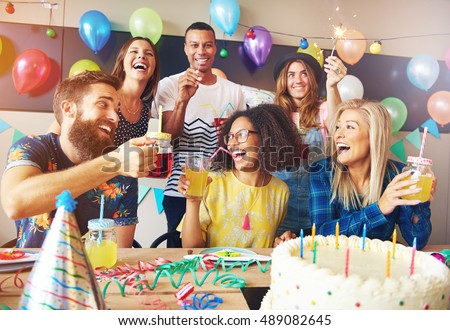 Happy exuberant group of friends celebrating a birthday party toasting the birthday girl laughing and joking