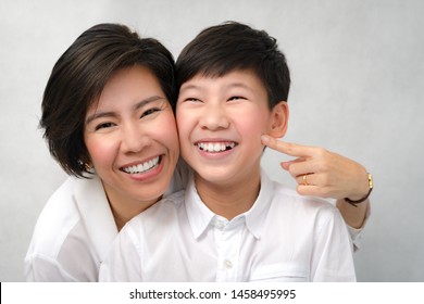 A Happy Face Of Asian Smart Looking Preteen Boy And Mom Laughing Together. Deciduous Teeth, Milk Teeth, Healthy And Strong, Dental Oral Care, Bonding, Mother And Son, Studio Portrait White Background.