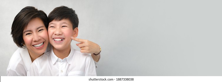 A happy face of asian smart looking preteen boy and mom laughing together. Deciduous teeth, Milk teeth, Healthy Dental oral care, Bonding, Mother and son, Studio portrait white background. Banner.