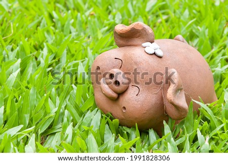 Happy face old female piggy clay sculpture in beautiful green carpet grass backyard garden ,empty copy space for text quote or background usage under happy feeling and animal with nature work concept