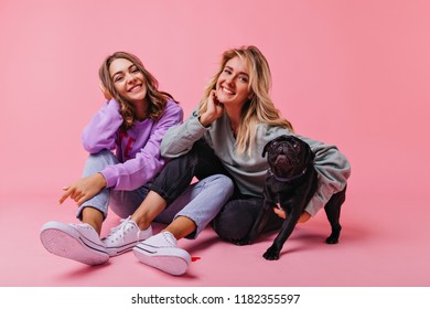 Happy Fair-haired Girl Embracing Bulldog Puppy. Enchanting Female Friends Relaxing In Studio During Photoshoot With Pet.