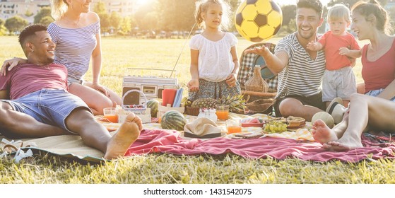 Happy families making picnic in city park - Young parents having fun with their children in summer time eating, laughing and playing together - Love and chlidood concept - Main focus on people faces - Powered by Shutterstock