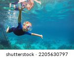 Happy family - active kid in wetsuit and snorkeling mask dive underwater, see tropical fishes in coral reef sea pool. Travel adventure, swimming activity on summer beach vacation with child.