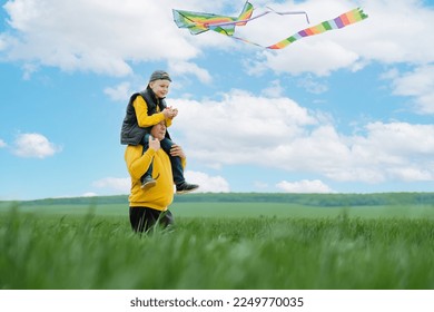 Happy family active outdoors games. child sitting at grandfather's on shoulders and launches fly a kite. Family holiday and enjoy good quality time. High quality photo