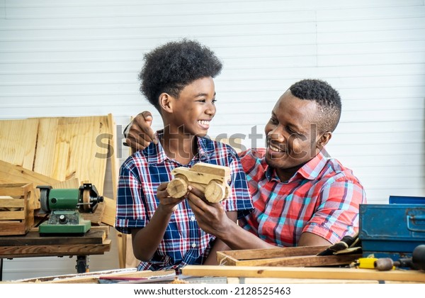 Happy
family african american father and son carpenter gather craft a car
out of wood and play, family concept to stay at home and enjoy good
relationship hobby together craftsman or
carpenter